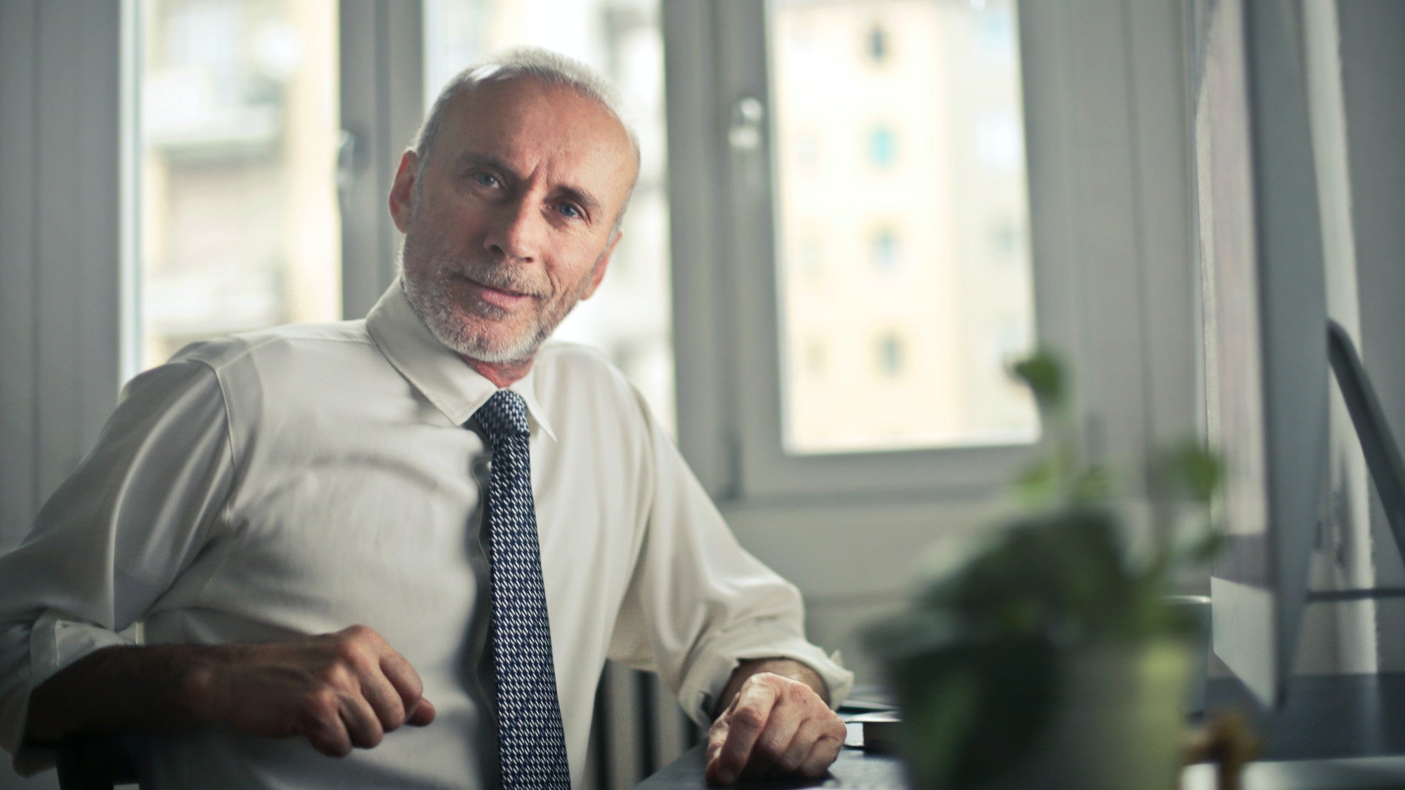 Older man sitting at a desk in a suit