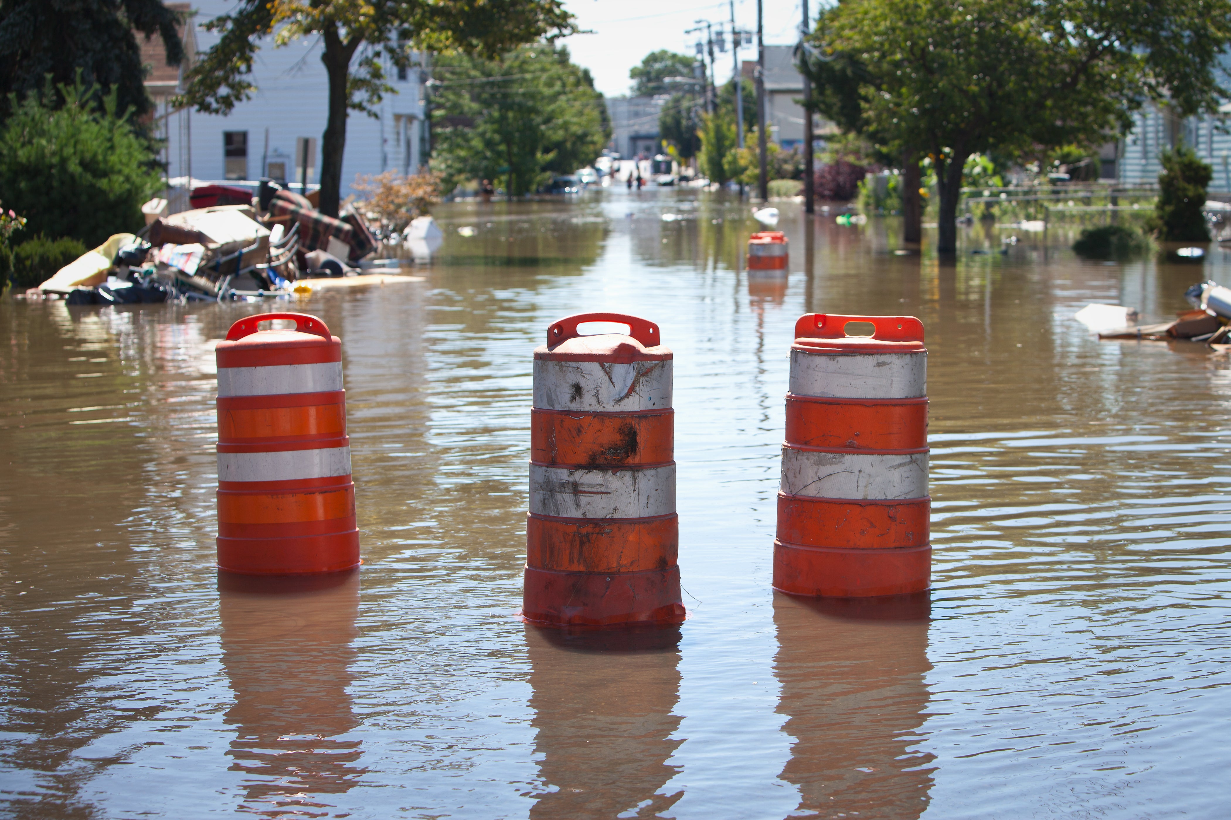 Orange and white barricades on a flooded road.