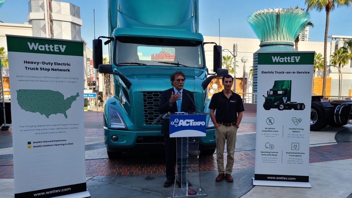 Mario Cordero, executive director of the Port of Long Beach, and Salim Youssefzadeh, co-founder of WattEV with a green Volvo VNR Electric truck behind them at a press conference.