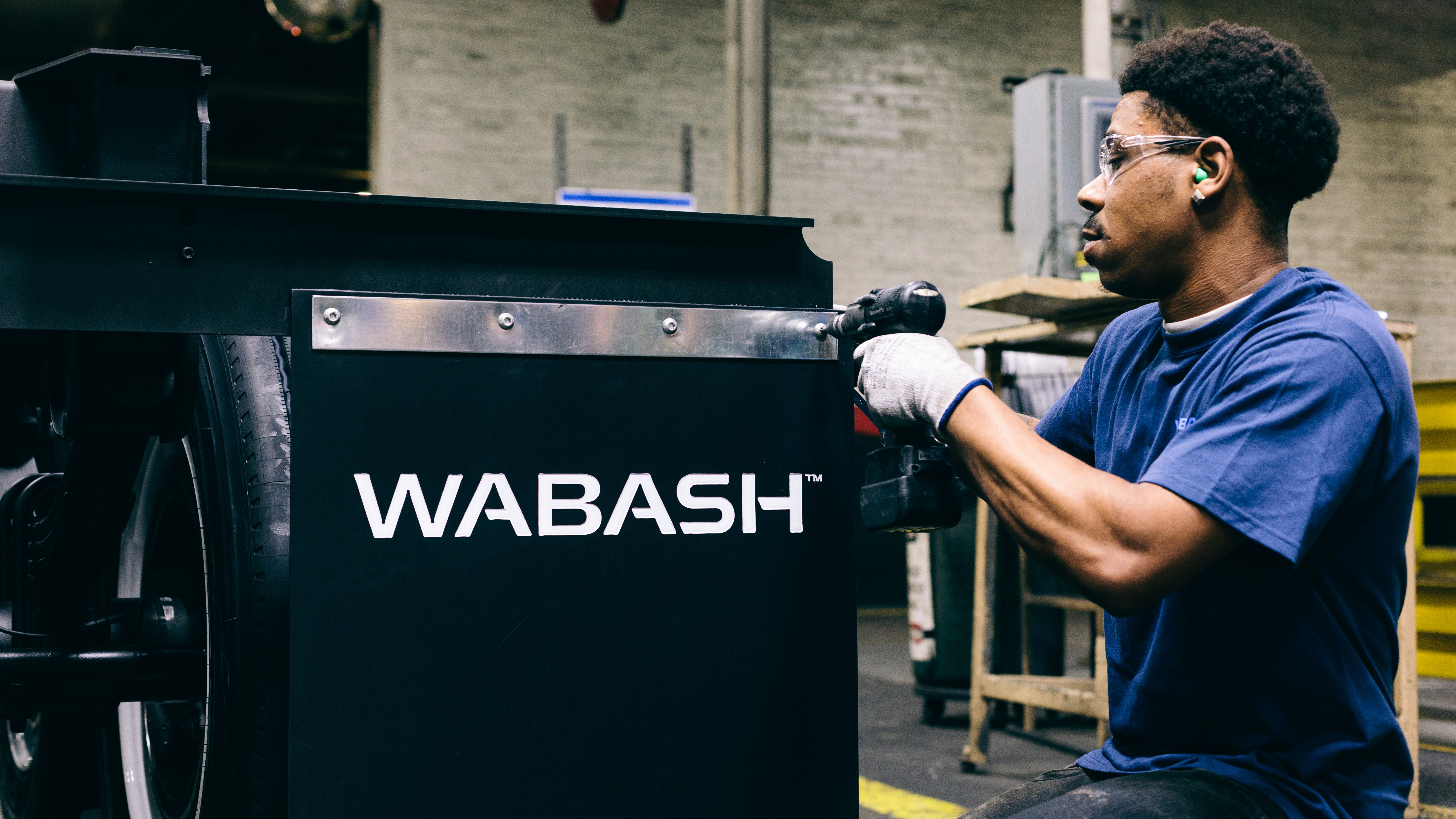 Worker affixing black Wabash mud flap to a trailer