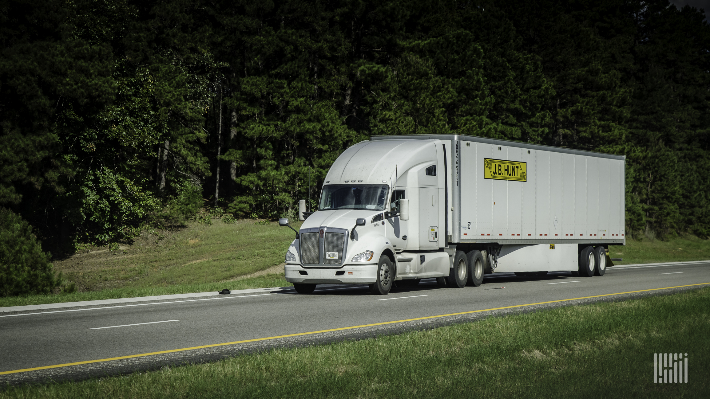 A white J.B. Hunt tractor pulling a white trailer on highway