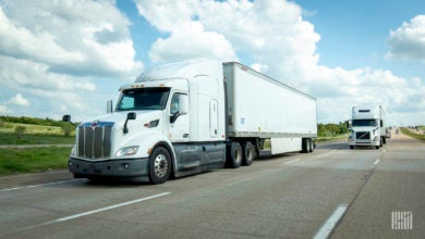 Two white tractor-trailers on a highway