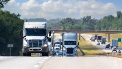 Several big trucks traveling both directions on a highway