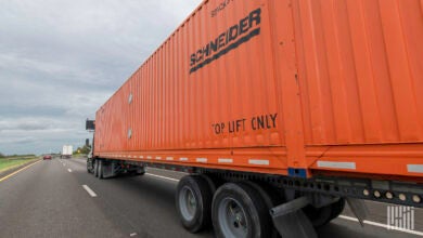 An orange Schneider intermodal container on the highway