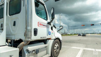 A white Trimac tractor at a stoplight