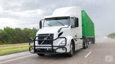 A white tractor pulling a green intermodal container