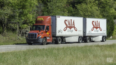 A red Saia tractor pulling two white Saia trailers